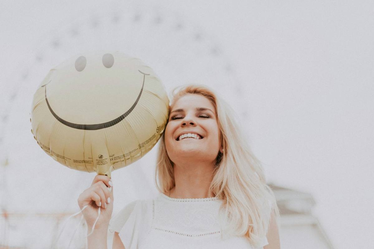 Smiling woman holding a balloon with a happy face, representing emotional relief and resilience after EMDR therapy.