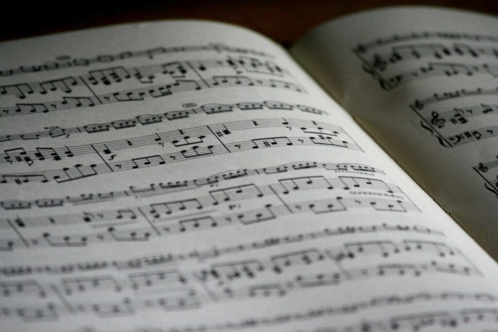 Open book of sheet music with musical notes, representing the role of music in therapy and healing.