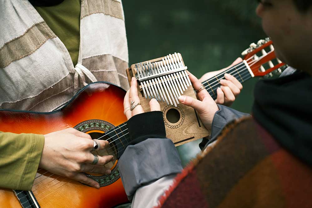 Two people playing guitar and kalimba together, representing connection, creativity, and emotional healing through EMDR therapy in Syracuse, NY.