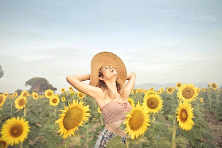 Woman smiling in a sunflower field symbolizing healing and hope from C-PTSD through therapy