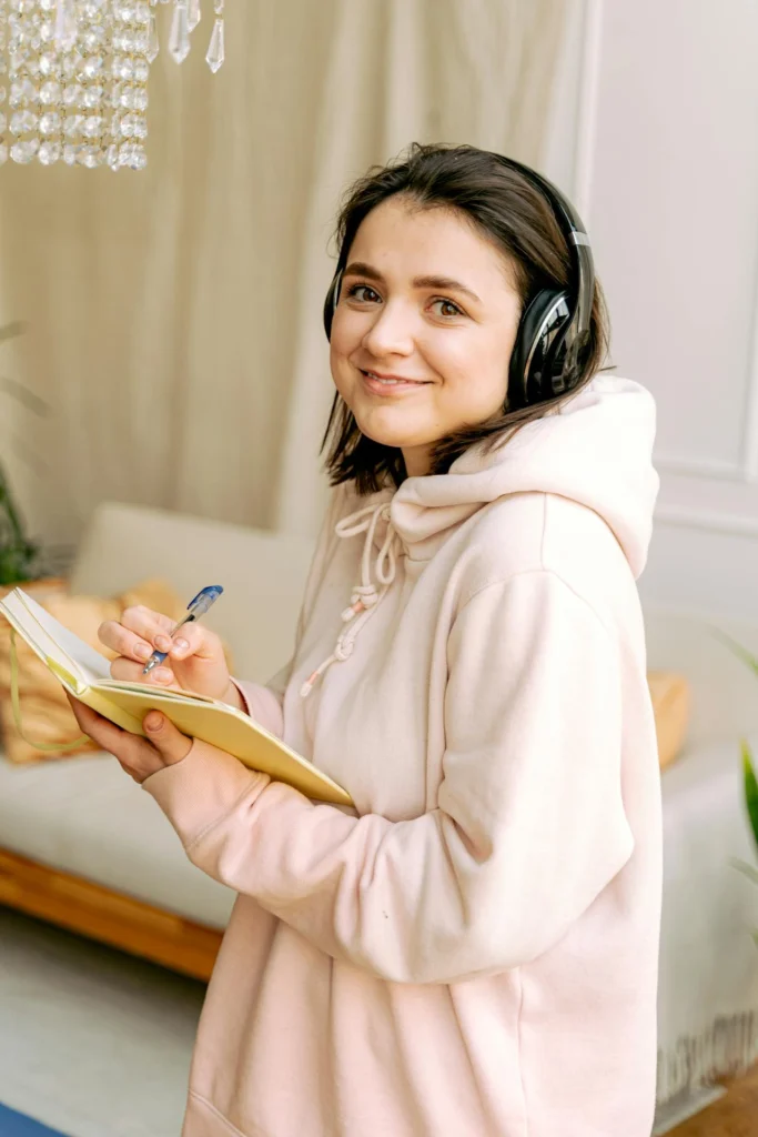 Woman listening to music and writing on notepad