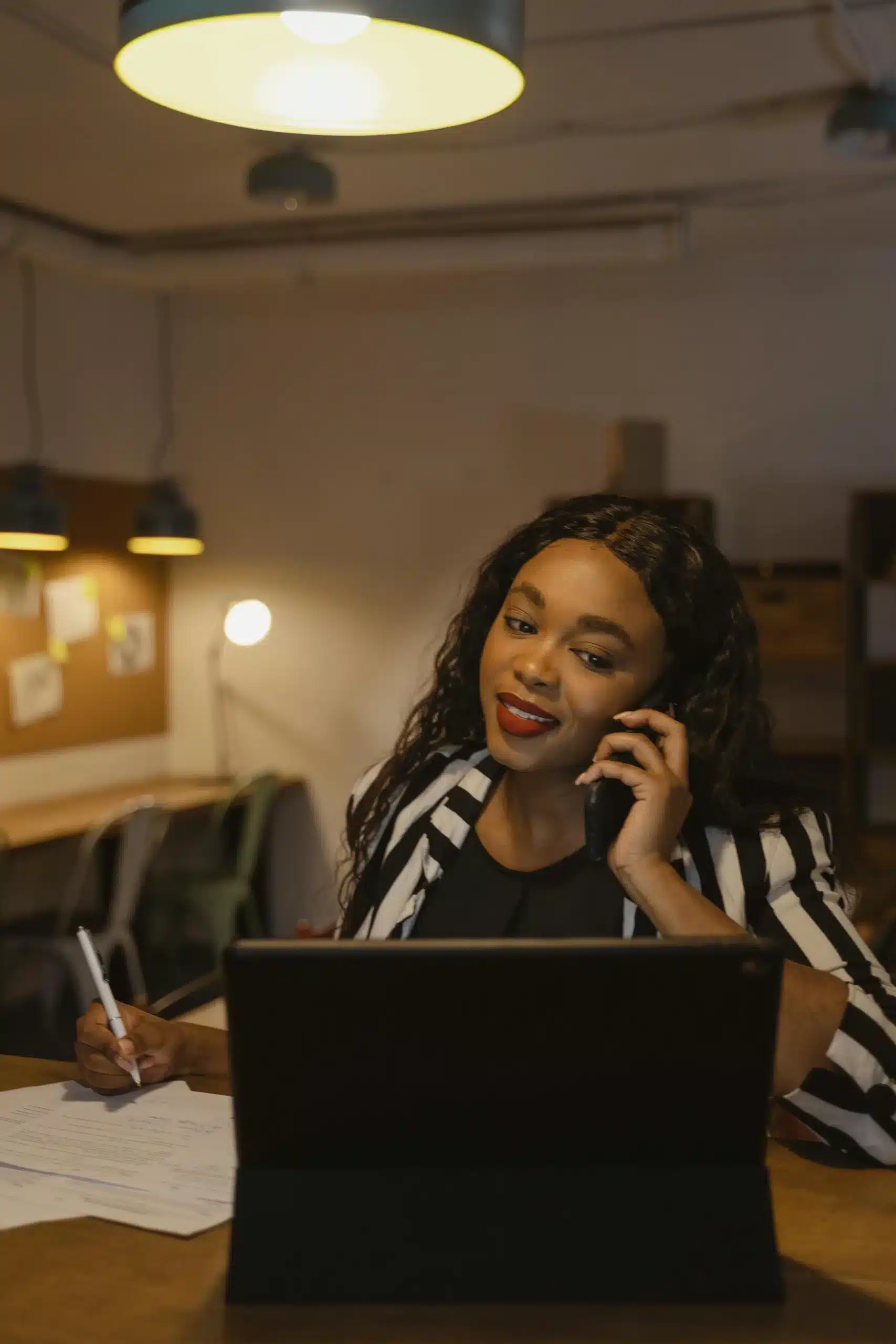 African American woman working late at night in an office, writing on her laptop in a quiet, focused environment