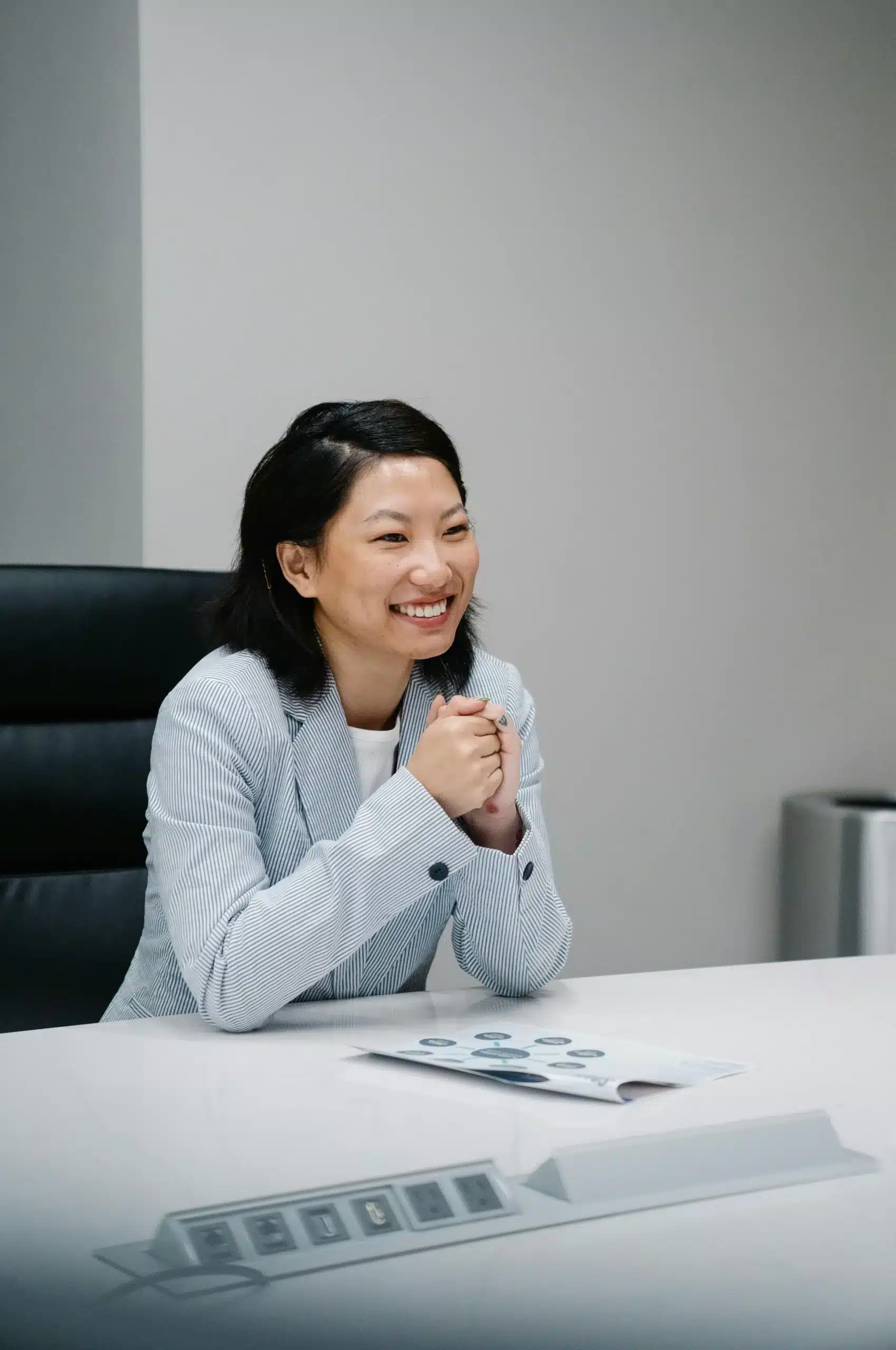 Asian American woman smiling in an office chair, reflecting focus and calm after Music Therapy for ADHD in Austin, Texas
