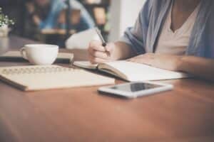 Person journaling at a desk with coffee, representing reflection and coping tools for high-functioning anxiety
