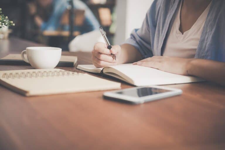 Person journaling at a desk with coffee, representing reflection and coping tools for high-functioning anxiety