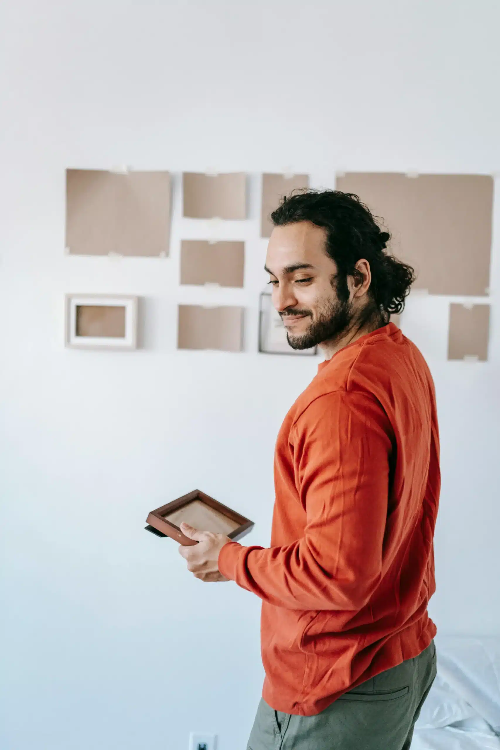  A man putting up photo frames, symbolizing personal expression, identity, and creating meaningful space.