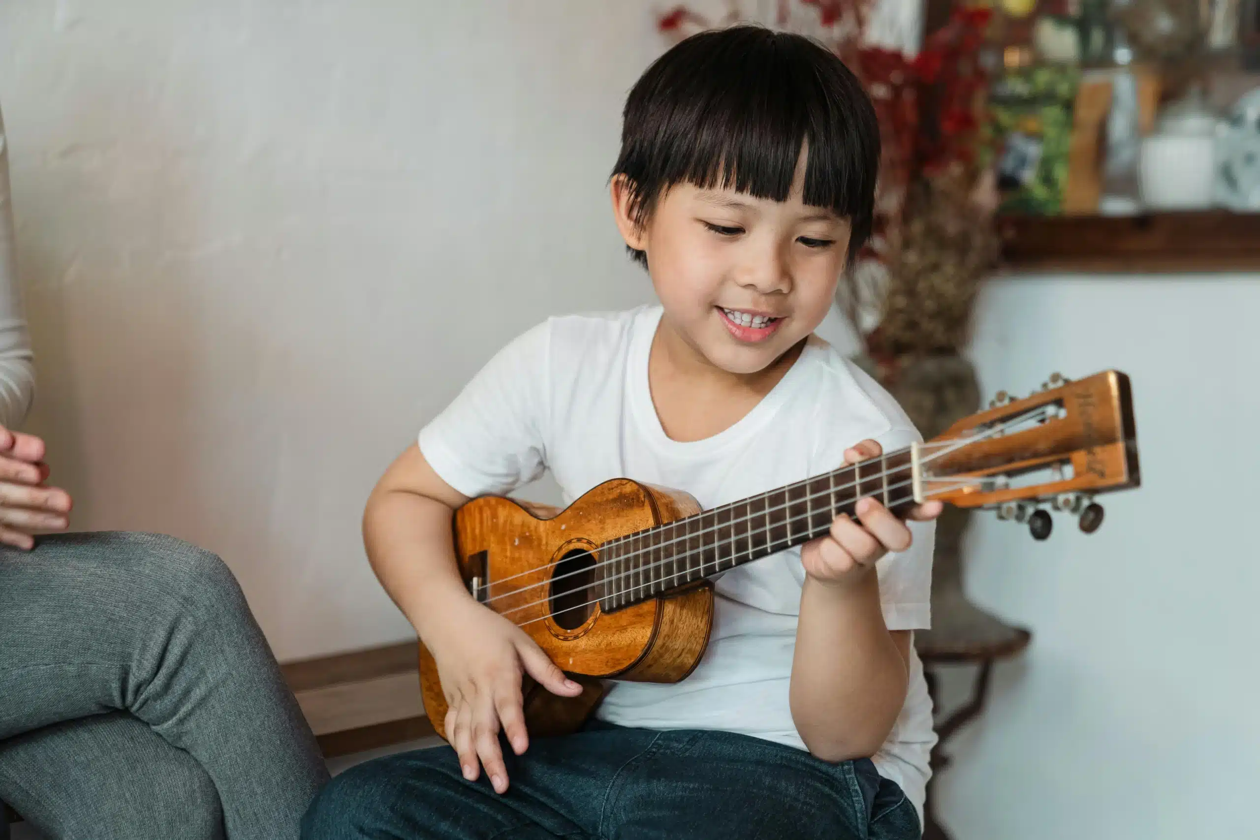 Asian boy playing guitar focused and engaged building confidence creativity and emotional expression through music play
