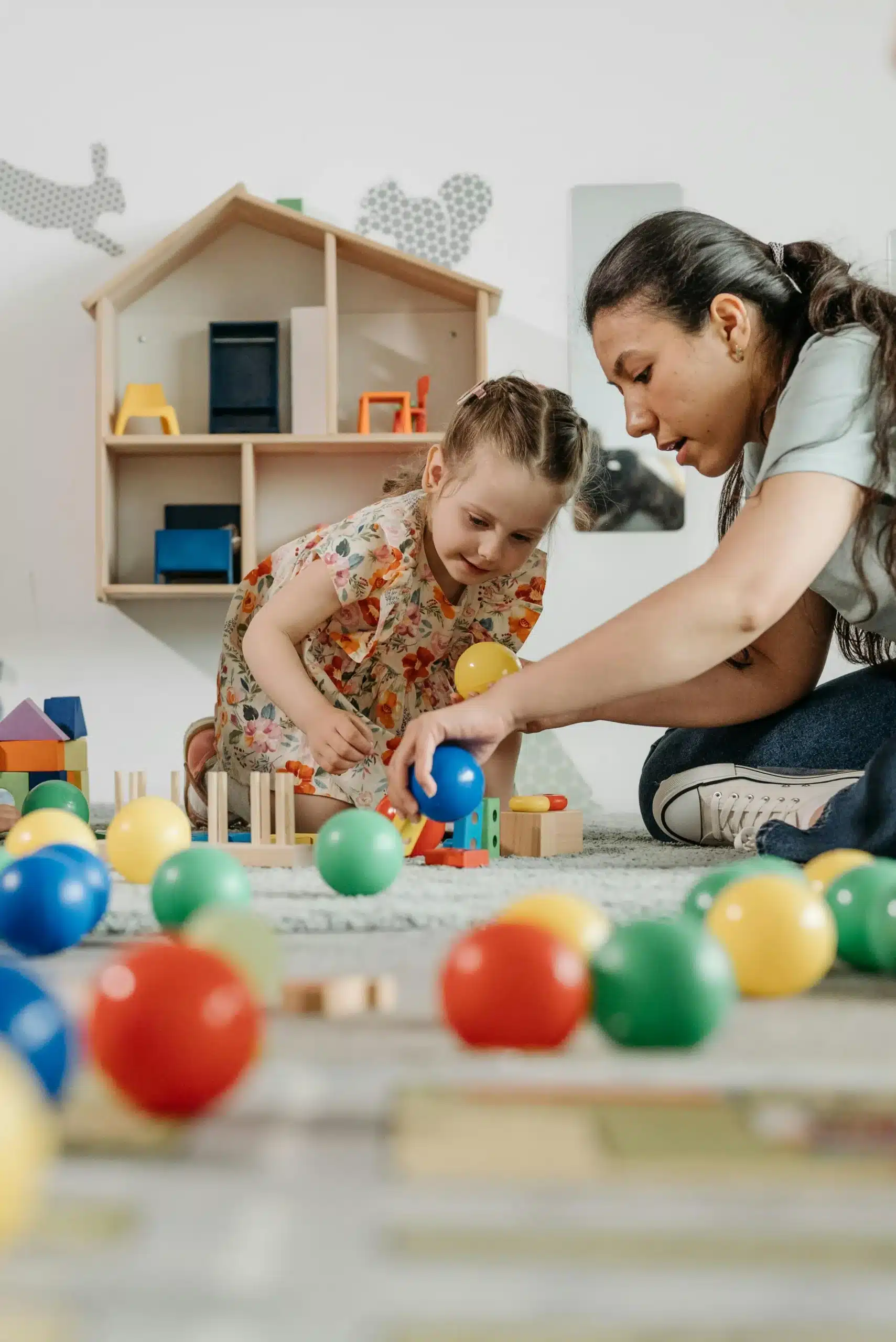 Mother and daughter playing with colorful balls encouraging bonding joy coordination and playful emotional development