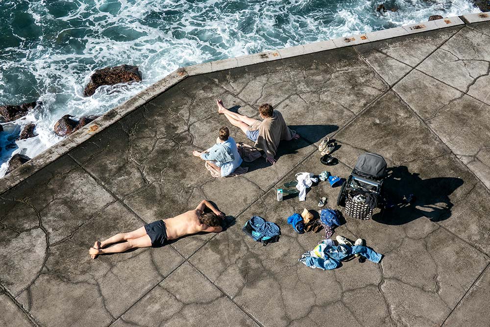 people relaxing on a concrete surface by the ocean