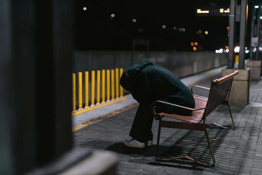 A person sitting on a bench with their head down