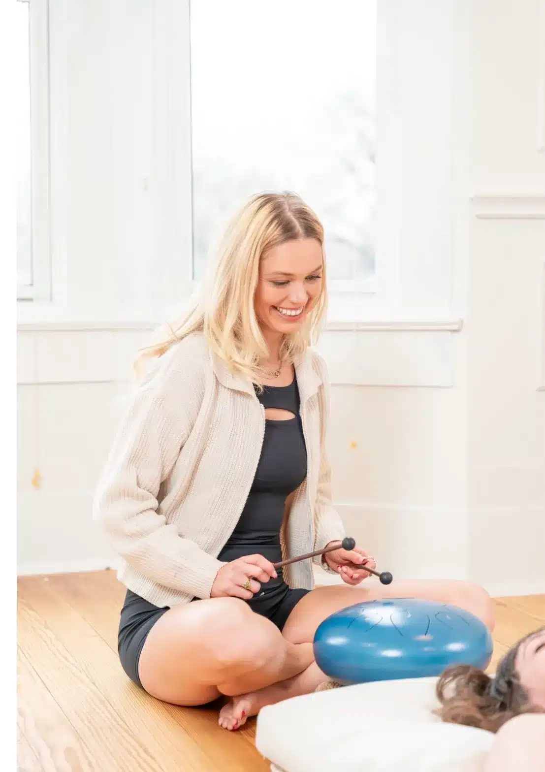 Professional wellness coach using sound therapy tools to guide a client through a calming