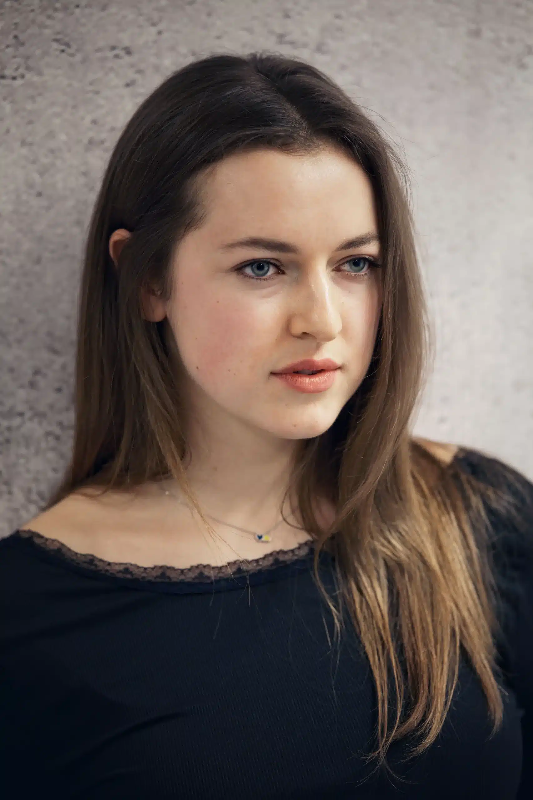 A portrait of a woman with long hair against a textured background