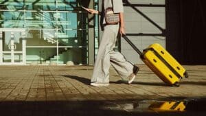 Woman with a suitcase walks in front of a building