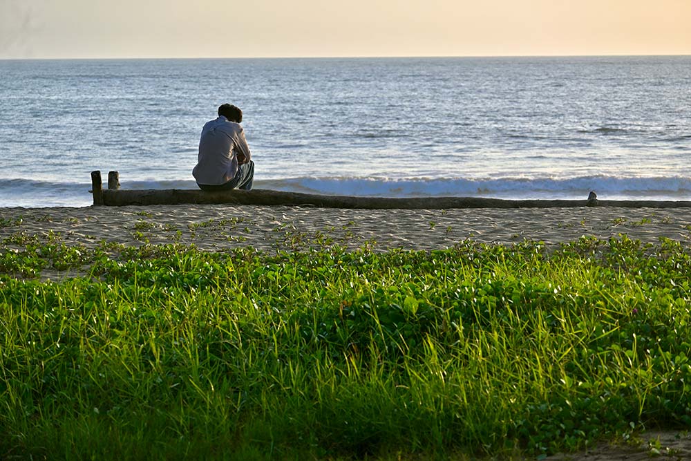 a man sitting on a bench looking out at the ocean