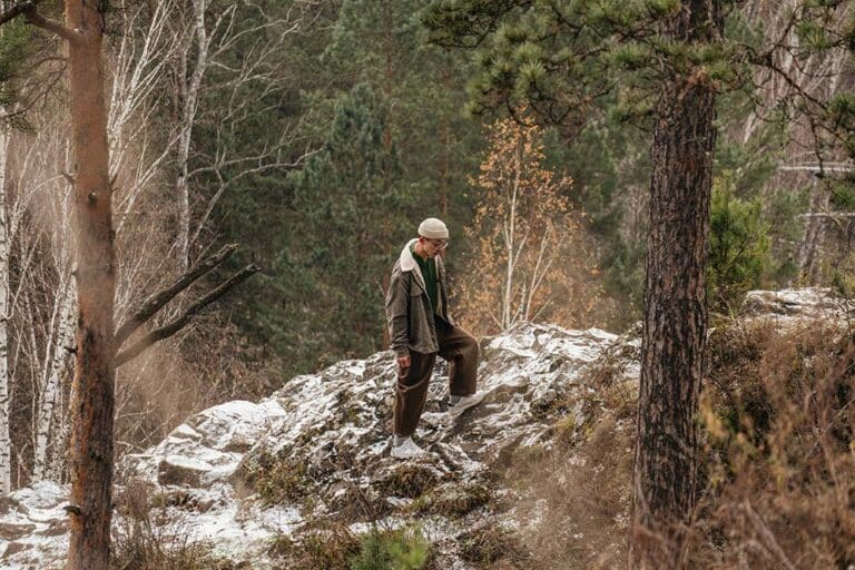 man walking on rocky terrain in a snowy forest