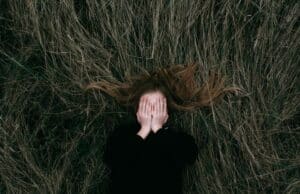 woman in black long sleeve shirt lying on brown grass field