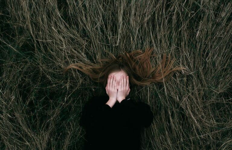woman in black long sleeve shirt lying on brown grass field