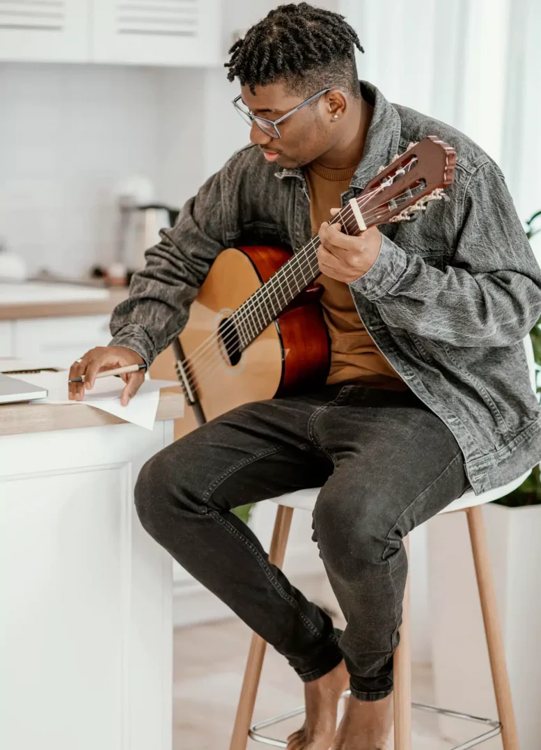 African American man writing notes while playing music