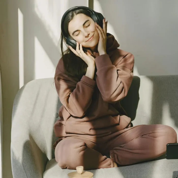  A girl wearing headphones with eyes closed, expressing calm, emotional connection, and immersive sensory experience.