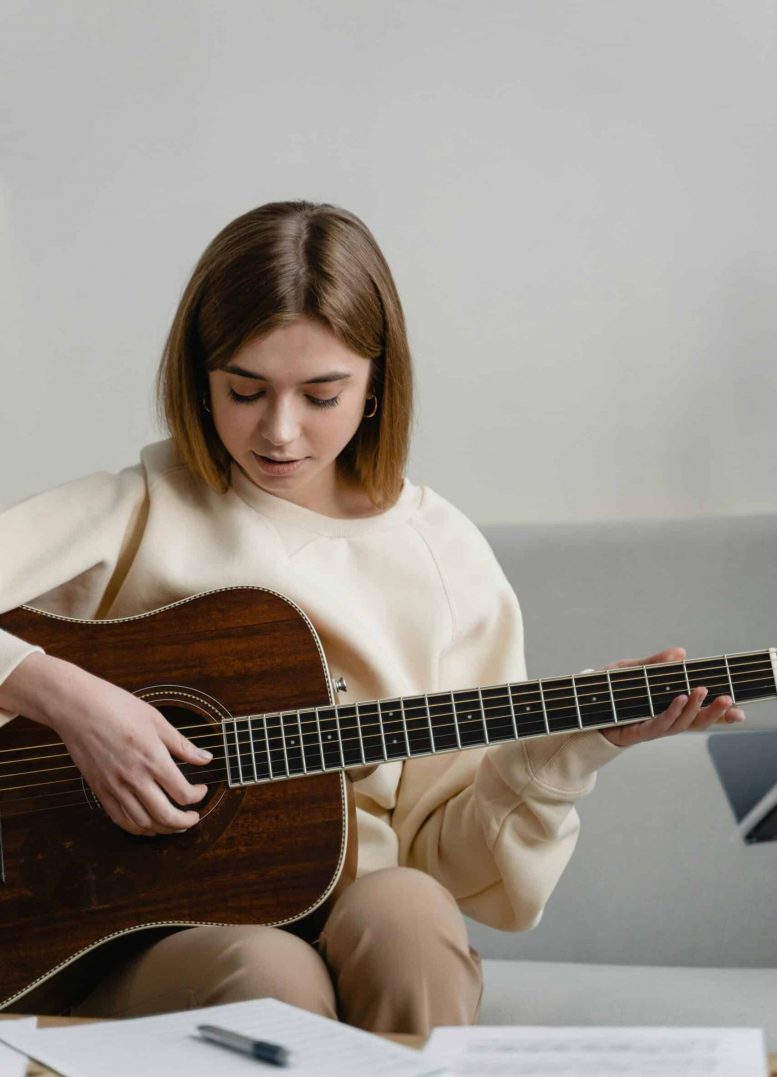A girl playing guitar symbolizes creativity, self-expression, and emotional connection through music therapy.